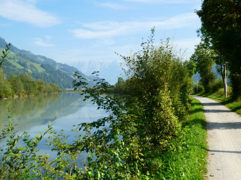 das Bild zeigt links den Fluss Salzach bei St. Johann im Pongau und rechts einen Fahrradweg, der am Fluß entlang führt