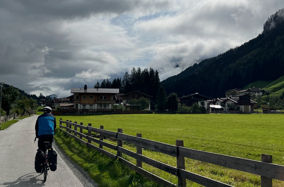 ein Fahrradfahrer fährt an einer Weide entlang, der Himmel ist wolkenbedeckt